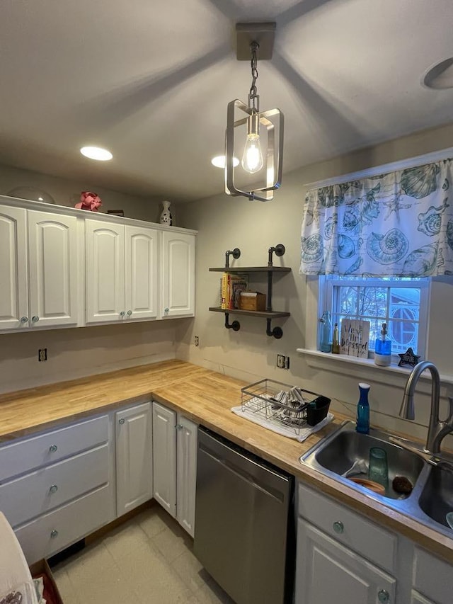 kitchen with decorative light fixtures, butcher block counters, stainless steel dishwasher, white cabinetry, and a sink