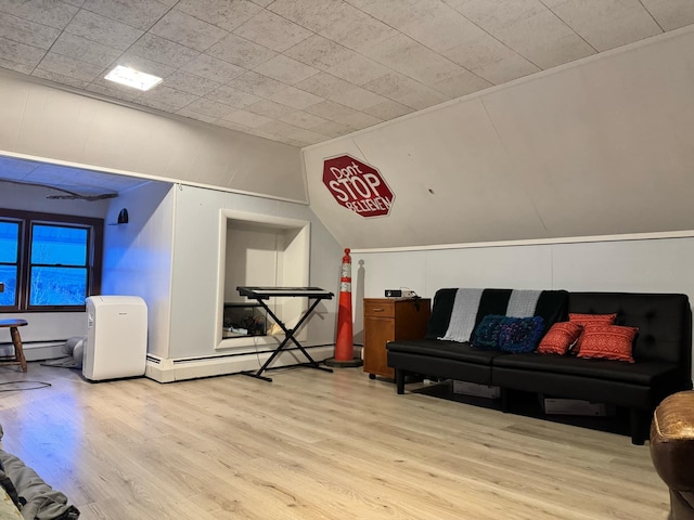 interior space featuring lofted ceiling, baseboard heating, and wood finished floors