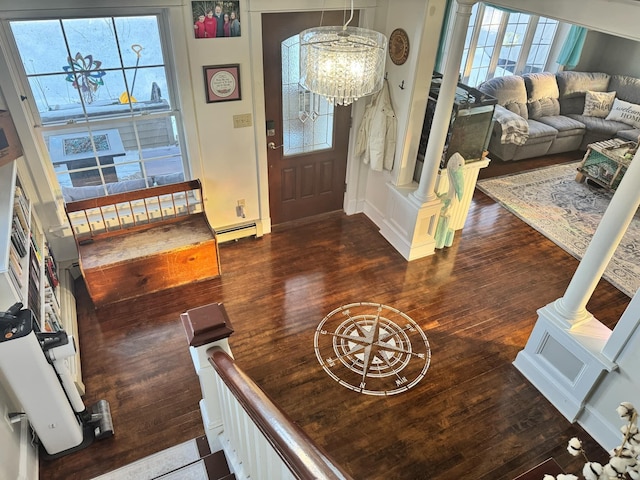 foyer entrance featuring ornate columns, plenty of natural light, baseboard heating, and wood finished floors