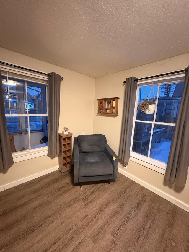 living area featuring dark wood-style floors, a textured ceiling, and baseboards