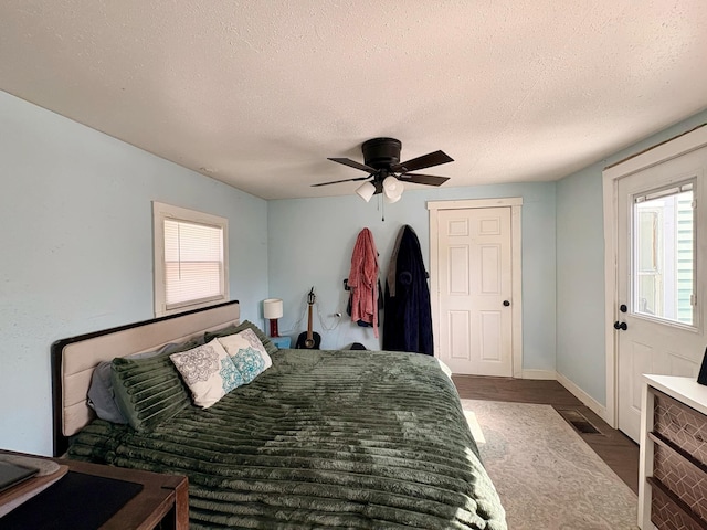 bedroom with ceiling fan, visible vents, a textured ceiling, and dark wood finished floors