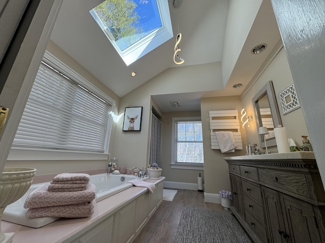 full bath featuring baseboards, lofted ceiling with skylight, a garden tub, wood finished floors, and vanity