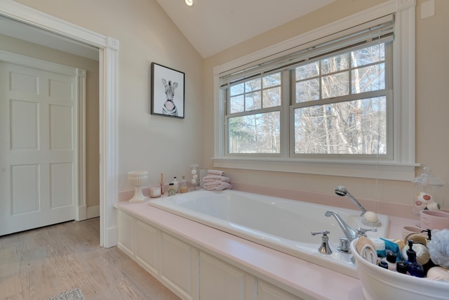 full bath with wood finished floors, a bath, and vaulted ceiling