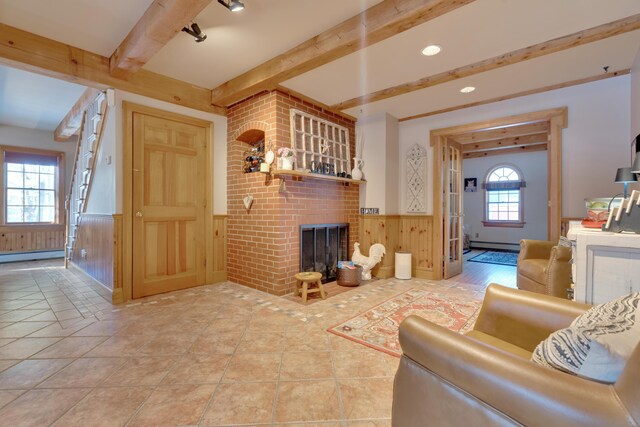 living room with tile patterned flooring, a wainscoted wall, wood walls, beam ceiling, and a fireplace