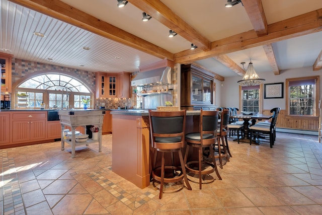 bar featuring beamed ceiling, wall chimney exhaust hood, light tile patterned floors, and a baseboard radiator