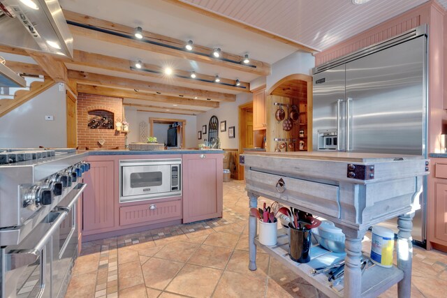 kitchen with light tile patterned floors, built in appliances, and beam ceiling