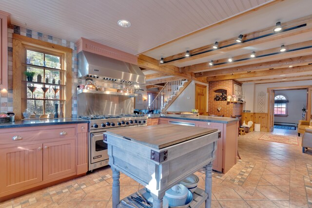 kitchen featuring luxury range, a wainscoted wall, beam ceiling, a peninsula, and wall chimney range hood