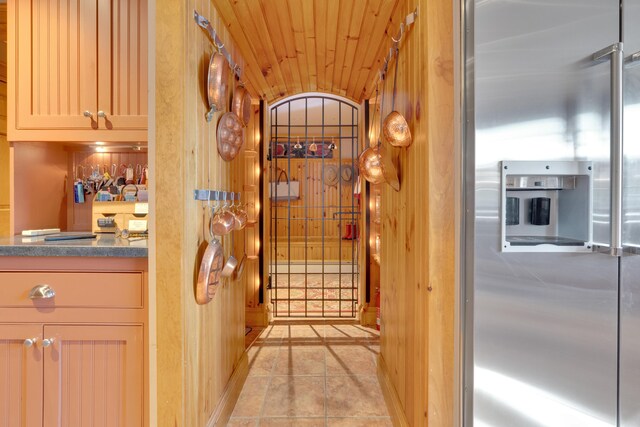 kitchen featuring light tile patterned flooring, stainless steel fridge, wooden ceiling, and dark countertops