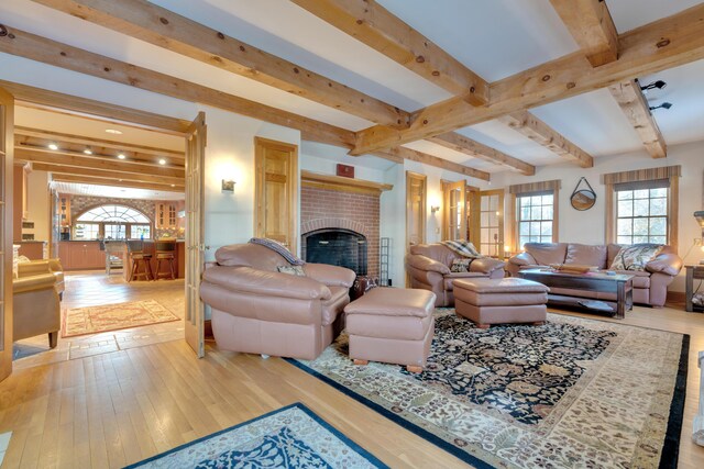 living area featuring beamed ceiling, wood-type flooring, and a fireplace