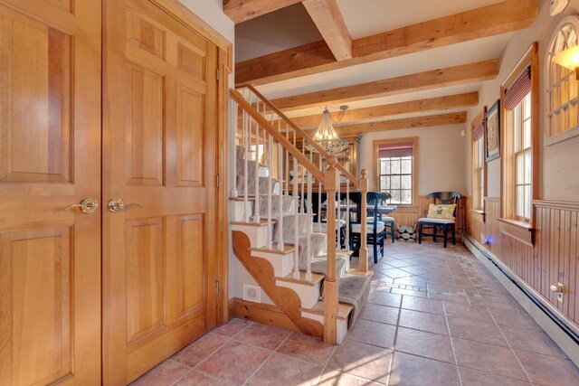 entrance foyer with a chandelier, baseboard heating, beamed ceiling, and stairs