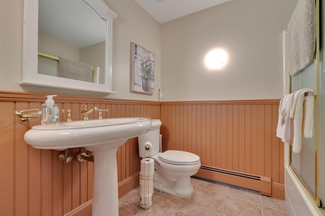 full bathroom featuring a baseboard heating unit, toilet, and wainscoting