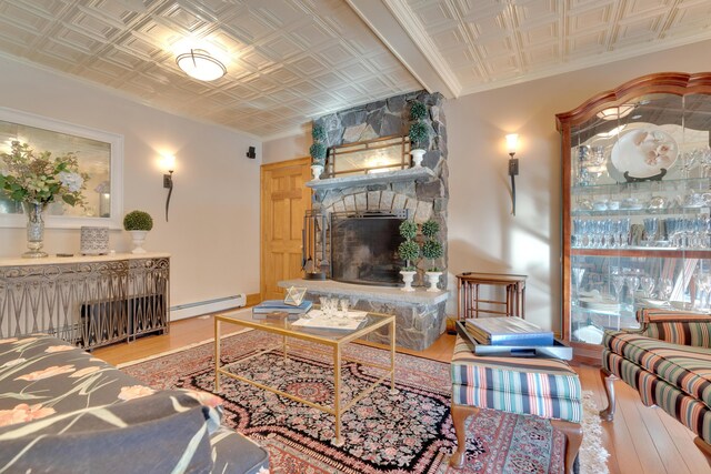 living area with an ornate ceiling, baseboard heating, wood finished floors, and a fireplace