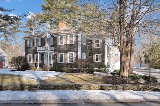 view of front of home with a chimney and a balcony