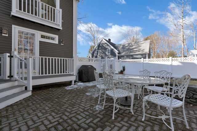 view of patio featuring a fenced backyard, a balcony, area for grilling, and outdoor dining space