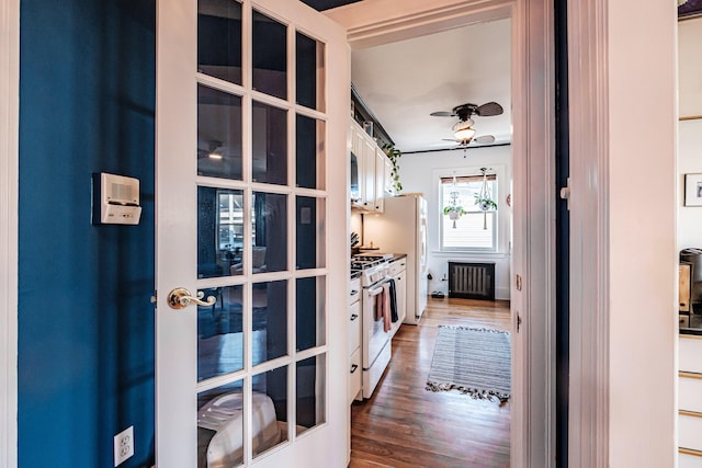 kitchen with radiator heating unit, wood finished floors, white gas range oven, and ceiling fan