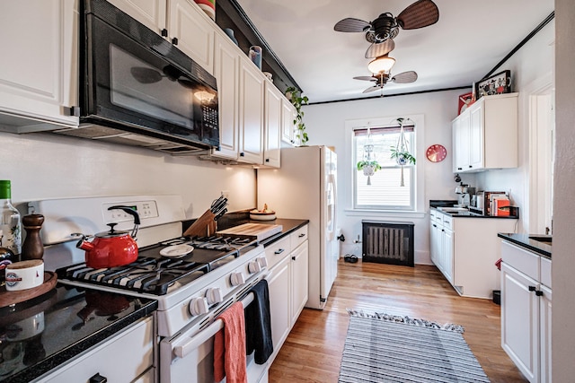 kitchen with light wood finished floors, ceiling fan, black microwave, white range with gas stovetop, and white cabinetry