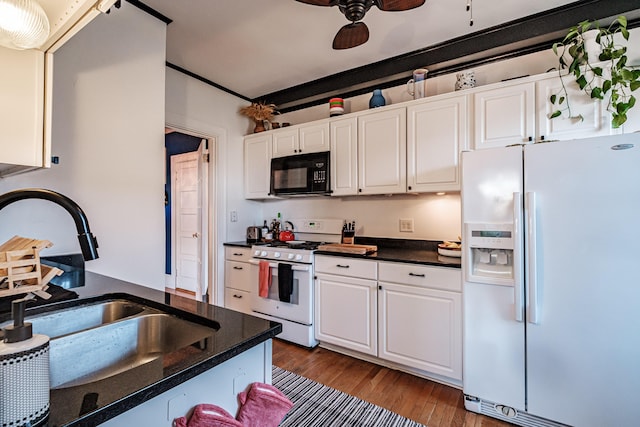 kitchen featuring a sink, white appliances, dark countertops, and dark wood-type flooring