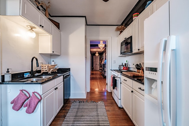 kitchen featuring a sink, dark countertops, dark wood-style floors, white cabinetry, and white appliances