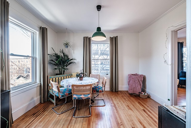 dining space with baseboards, crown molding, and light wood-style floors