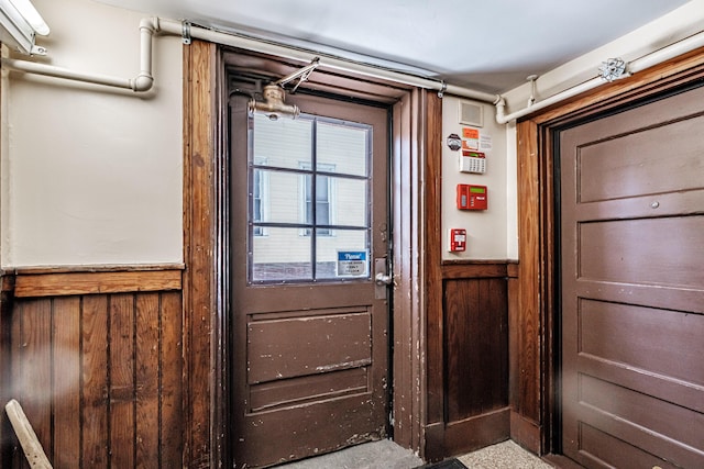 doorway to outside with a wainscoted wall and wood walls