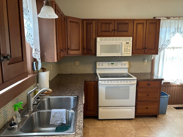 kitchen featuring visible vents, a sink, dark countertops, tasteful backsplash, and white appliances