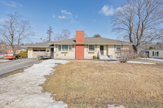 single story home with aphalt driveway, a chimney, a garage, and a front yard