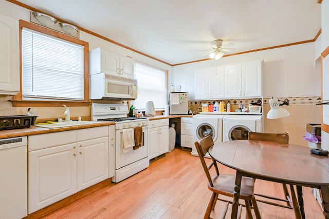 kitchen with white appliances, light wood-style flooring, ornamental molding, a sink, and independent washer and dryer