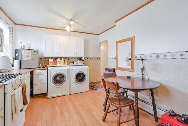 laundry room featuring light wood finished floors, laundry area, arched walkways, washer and dryer, and tile walls