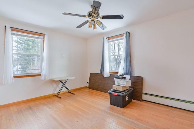 interior space featuring a wealth of natural light, baseboard heating, and light wood-style flooring