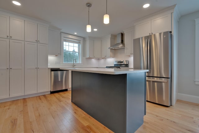 kitchen with decorative backsplash, light countertops, white cabinets, appliances with stainless steel finishes, and wall chimney range hood