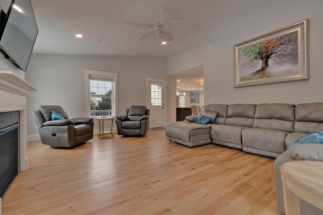 living room featuring recessed lighting, light wood-type flooring, lofted ceiling, and a fireplace