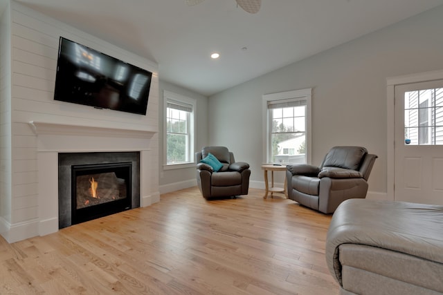 living room with wood finished floors, a glass covered fireplace, recessed lighting, baseboards, and vaulted ceiling