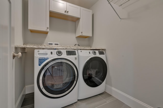 laundry area featuring cabinet space, washing machine and dryer, baseboards, and light tile patterned flooring