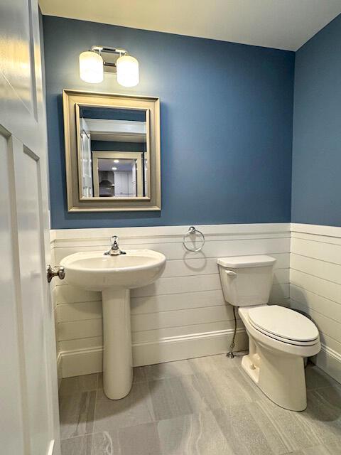 bathroom featuring a wainscoted wall and toilet