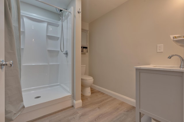 bathroom with toilet, a shower, baseboards, and wood finished floors