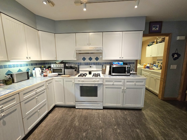 kitchen with white gas stove, dark wood-style flooring, light countertops, under cabinet range hood, and stainless steel microwave