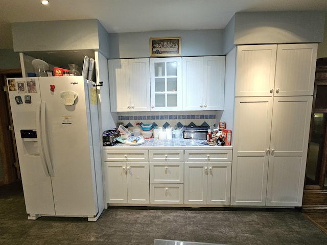 kitchen featuring backsplash, glass insert cabinets, light countertops, white fridge with ice dispenser, and white cabinetry