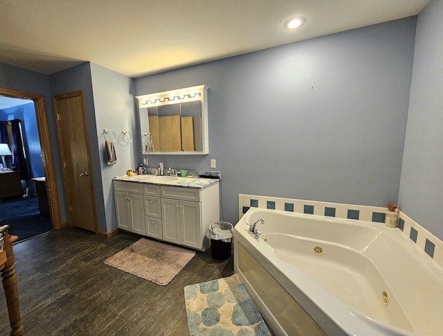 bathroom with a jetted tub, vanity, and wood finished floors