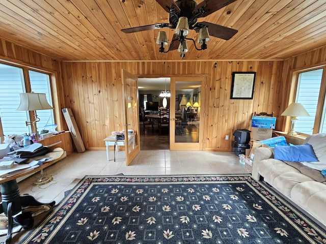 unfurnished living room with ceiling fan, wooden ceiling, and tile patterned flooring