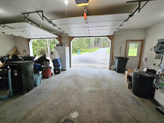 garage with a garage door opener and freestanding refrigerator