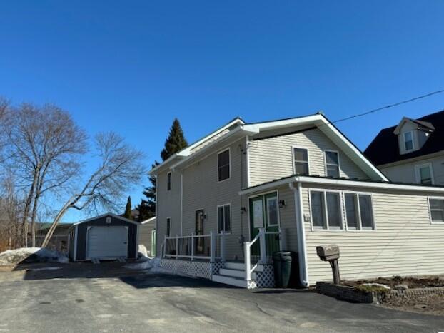 view of side of property with aphalt driveway, an outbuilding, and a garage