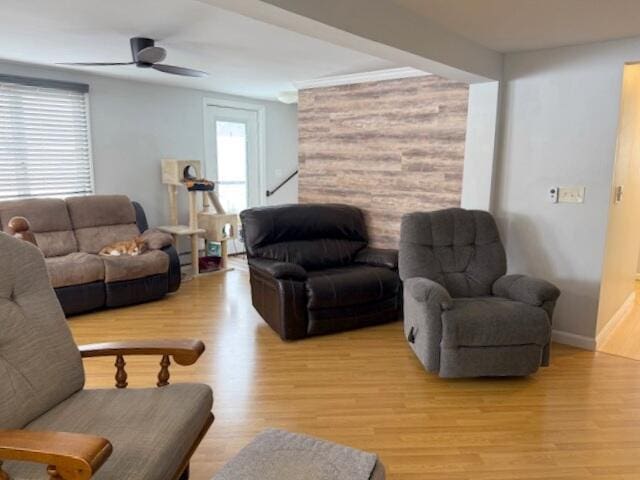 living area with baseboards, light wood-type flooring, and a ceiling fan