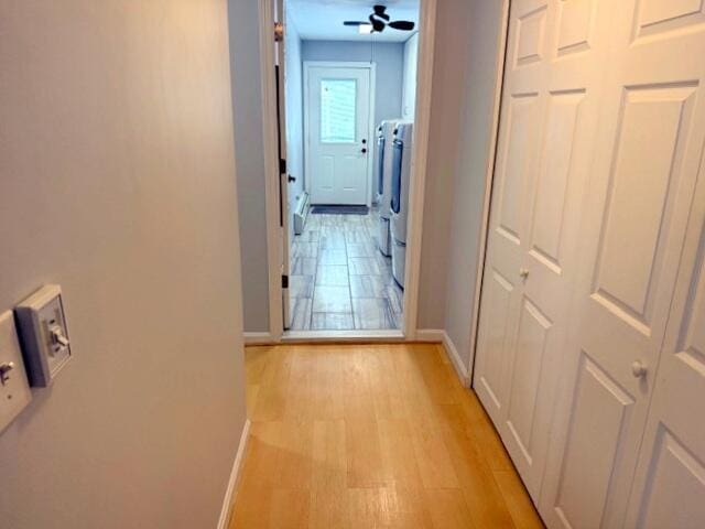 corridor featuring baseboards, light wood-style floors, and washer and clothes dryer