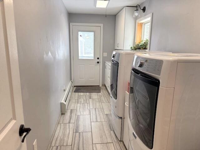 laundry area with cabinet space, baseboard heating, and washing machine and clothes dryer