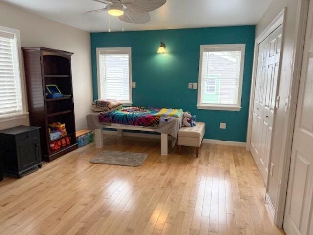 bedroom featuring baseboards, multiple windows, light wood-style floors, and a ceiling fan