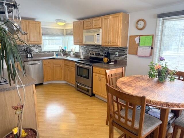 kitchen featuring tasteful backsplash, light brown cabinets, light wood-style flooring, appliances with stainless steel finishes, and a sink