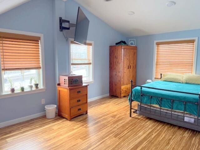 bedroom with baseboards, light wood-style floors, and vaulted ceiling