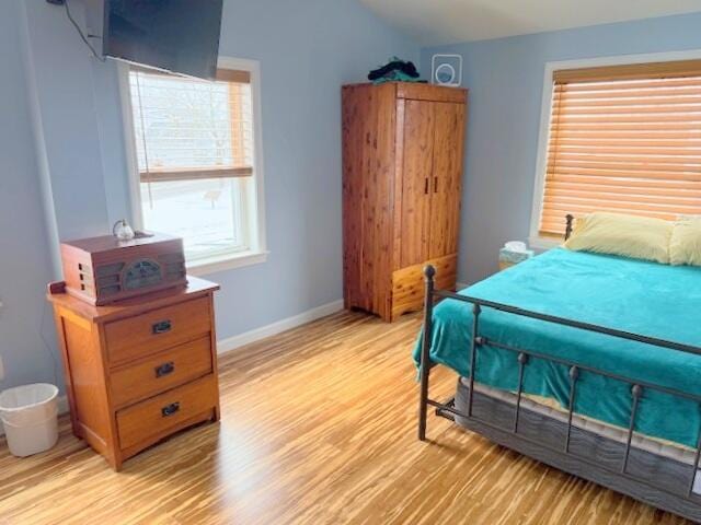 bedroom featuring vaulted ceiling, baseboards, and light wood finished floors