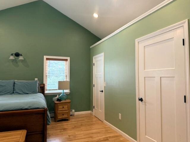 bedroom featuring light wood-style flooring, baseboards, and high vaulted ceiling