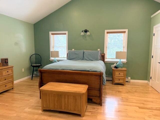 bedroom with baseboard heating, high vaulted ceiling, light wood-type flooring, and baseboards